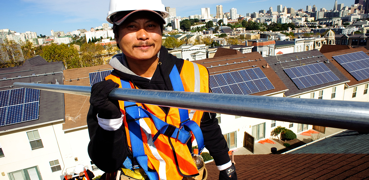 Construction worker wearing hard hard and holding metal pipe.